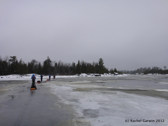 The group follows a ribbon of good, black ice across the middle of Little Gabbro Lake.